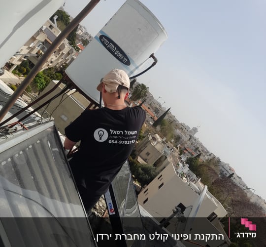 אדם עובד על דוד שמש על גג בניין